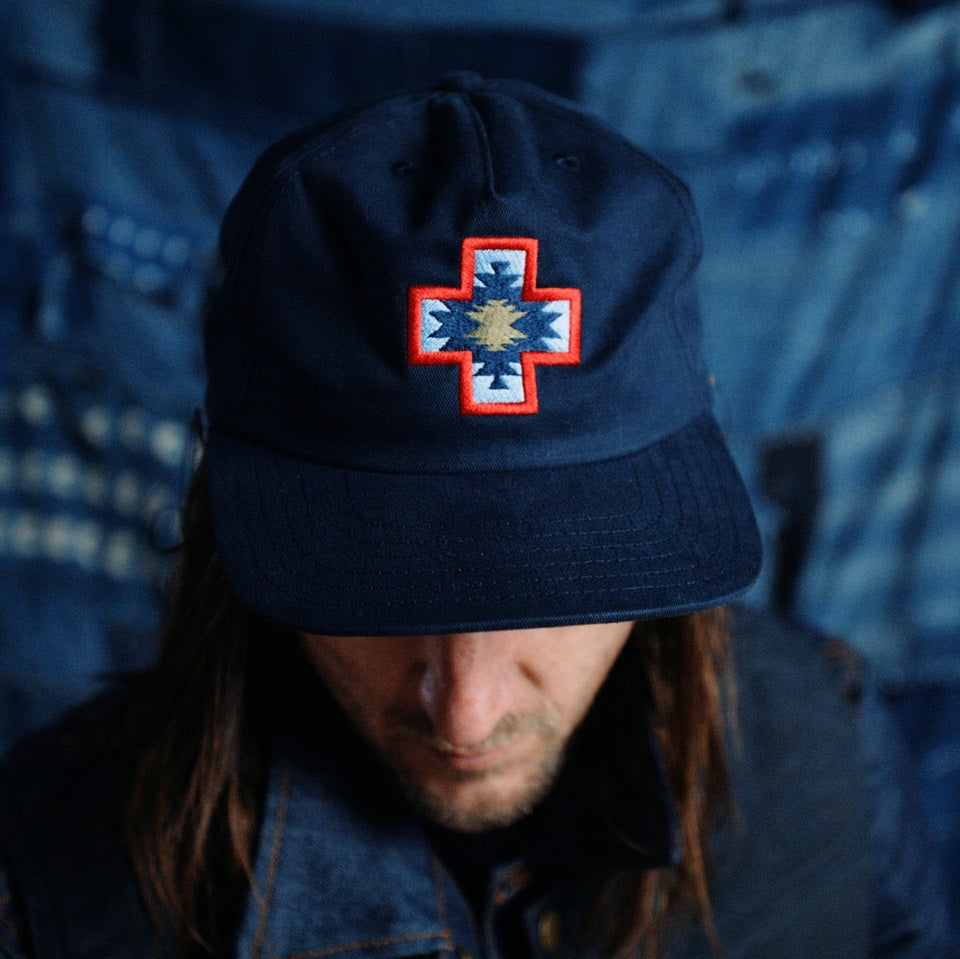 Embroidered twill navy hat with red blue and tan four direction symbol