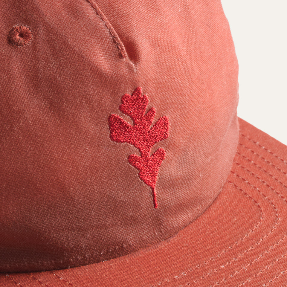 Close up of Light red wax canvas hat with Native American oak leaf embroidered on front