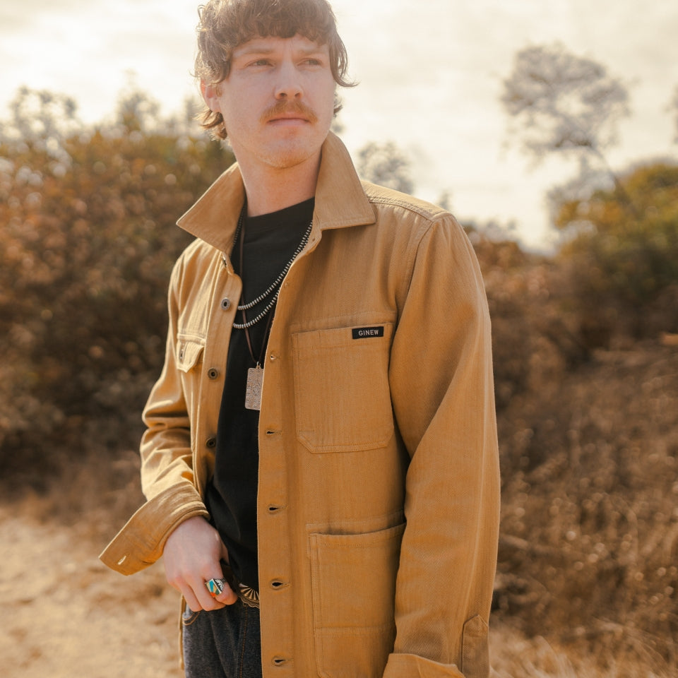man wearing tan saddle herringbone cotton chore barn jacket with black tee