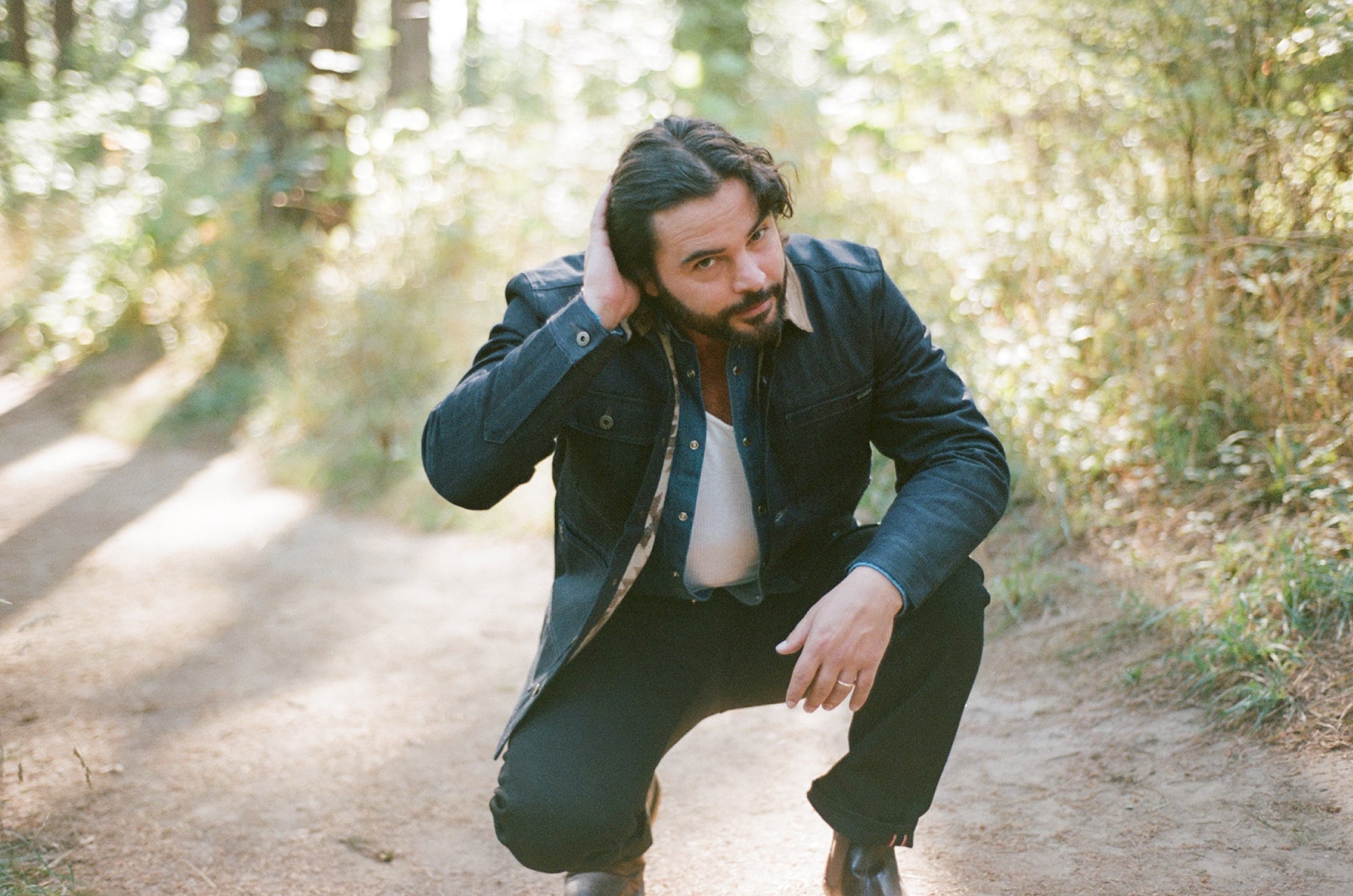 Man wearing a lined denim chore coat on a dirt path in a forest