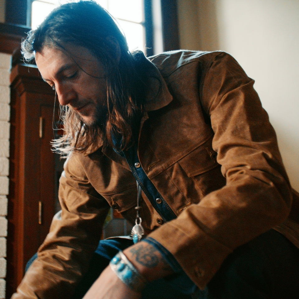 Brown wax canvas jacket by Ginew on male in living room