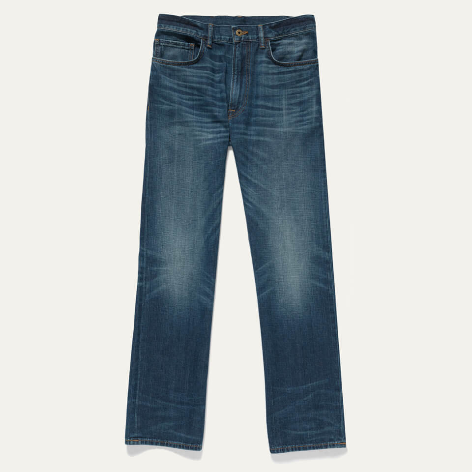 Raven Jean lay flat on a white background. Jean is a regular rise, full upper, tapered leg fit with a custom wash.