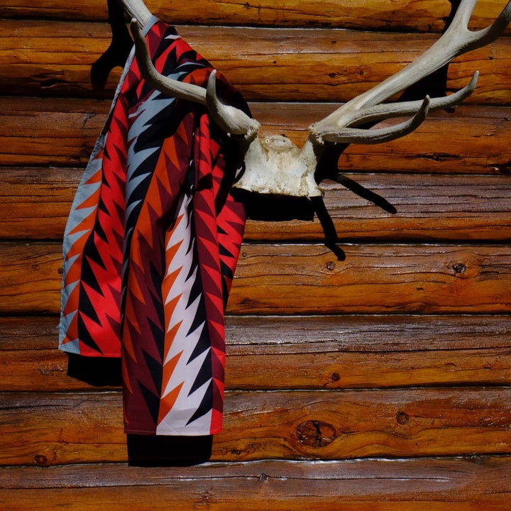 Gently Strikes Wild rag in red, black, sky blue and orange hanging on antlers