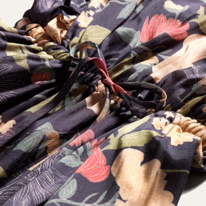 Close up of drawstring waist on Raw silk dress with flower print and ruffles. 