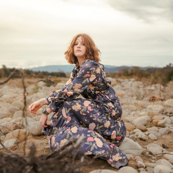 Woman in silk floral dress in rock field