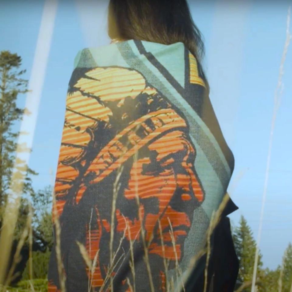 Native American designed wool blend blanket on Indigenous woman in field 