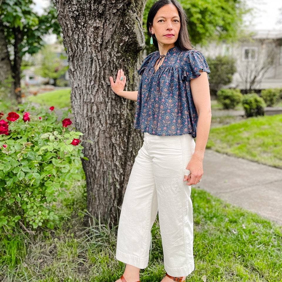 Ginew co-founder Amanda wearing cream carpenter pants and silk paisley ruffle shirt