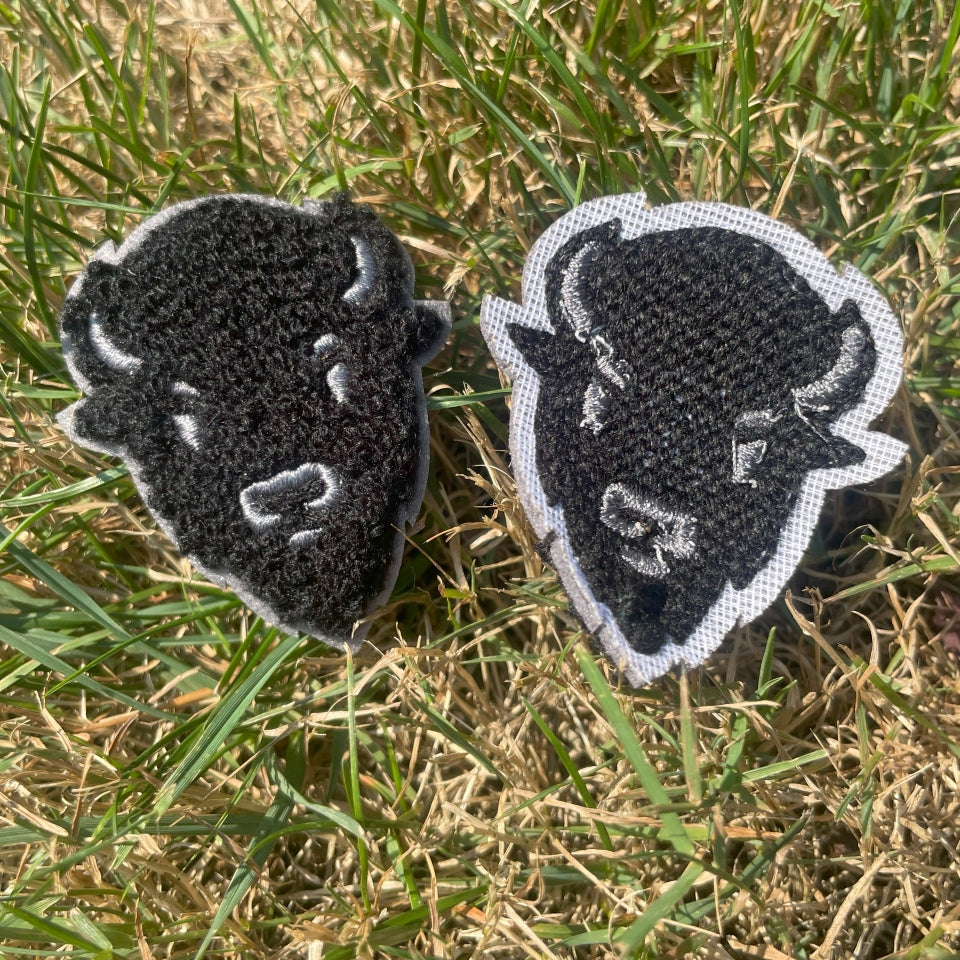 Two black and gray patches with a buffalo design on grass