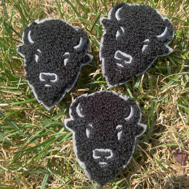 Three black and gray animal-shaped patches on grass