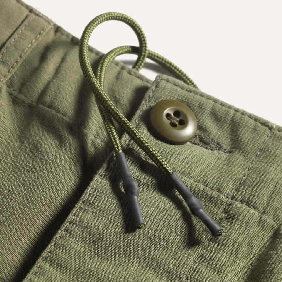 Detail view of waist drawstring and button fly on green ripstop Ginew Cargo Pants.