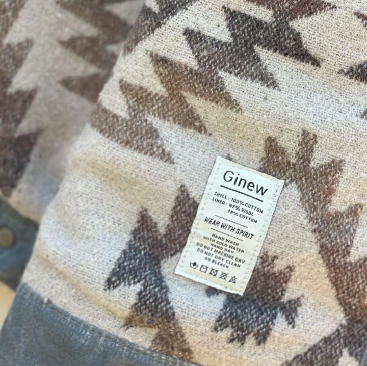 Care tag of Grey silver charcoal wax canvas rider coat lined with  Native American design in  brown and cream wool interior made by Indigenous owned Ginew