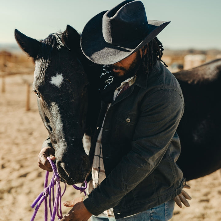 Rancher wearing black wax canvas coat made by Ginew