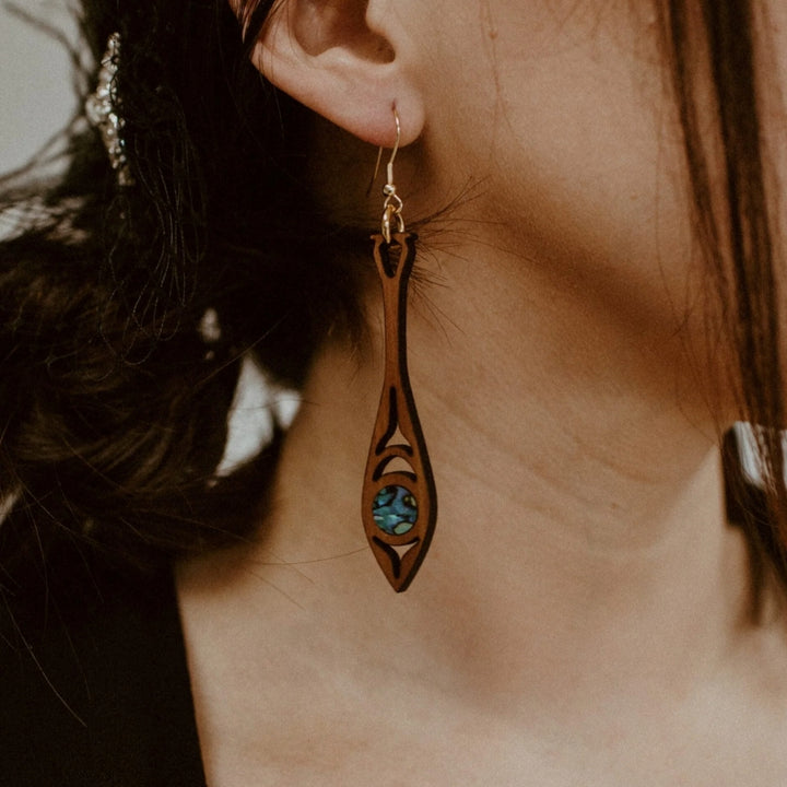 Paddle shaped earrings made of cedar wood and abalone worn and made by Native American women 