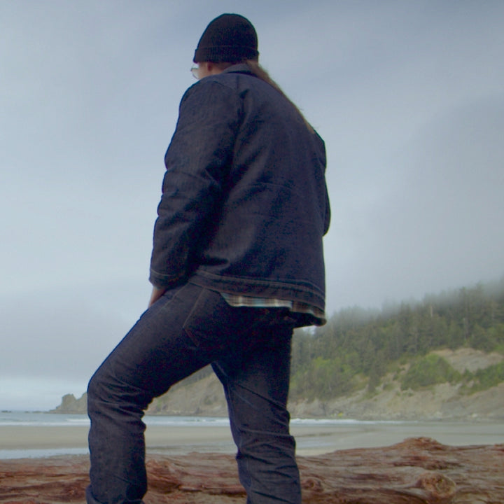 Man wearing black merino wool cap in denim at ocean