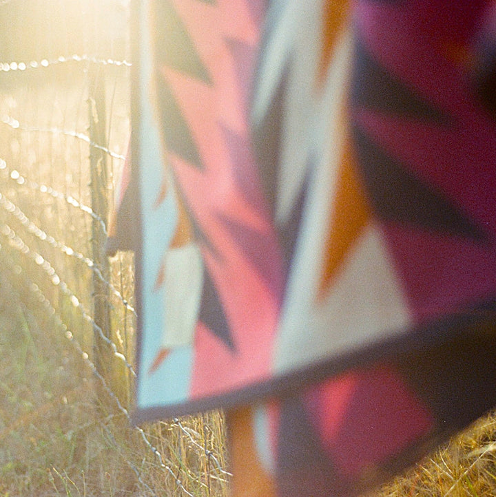 Colorful wool blanket Native American designed hanging over fence