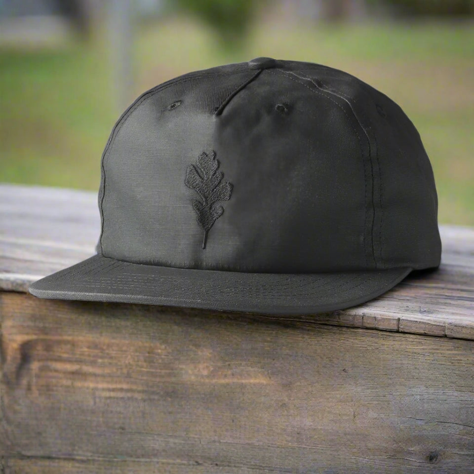 Black wax canvas hat with oak leaf on bench