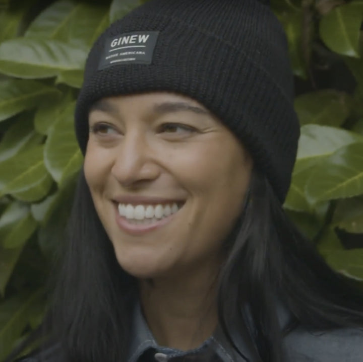 Native American Woman wearing black merino wool watch cap with foliage in background