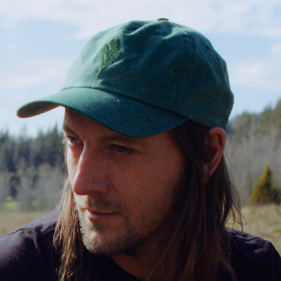 Green wax canvas hat with embroidered oak leaf on male model