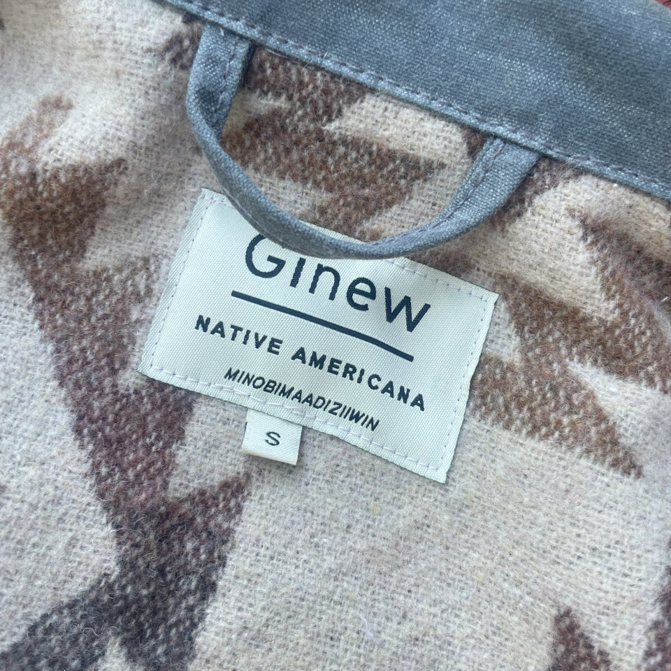 Tag on Grey silver charcoal wax canvas rider coat lined with  Native American design in  brown and cream wool interior made by Indigenous owned Ginew