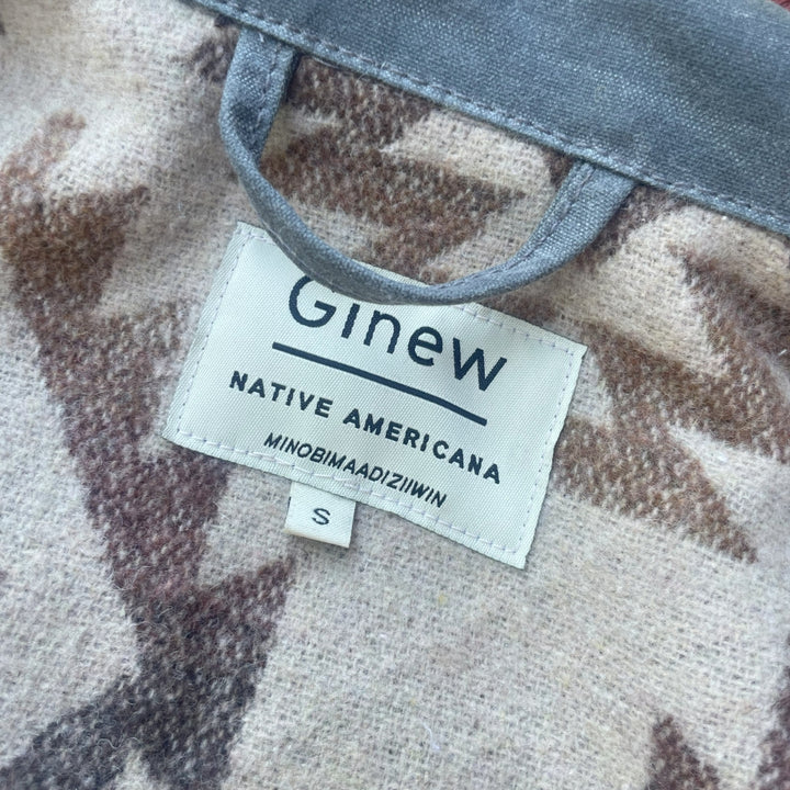 Tag on Grey silver charcoal wax canvas rider coat lined with  Native American design in  brown and cream wool interior made by Indigenous owned Ginew