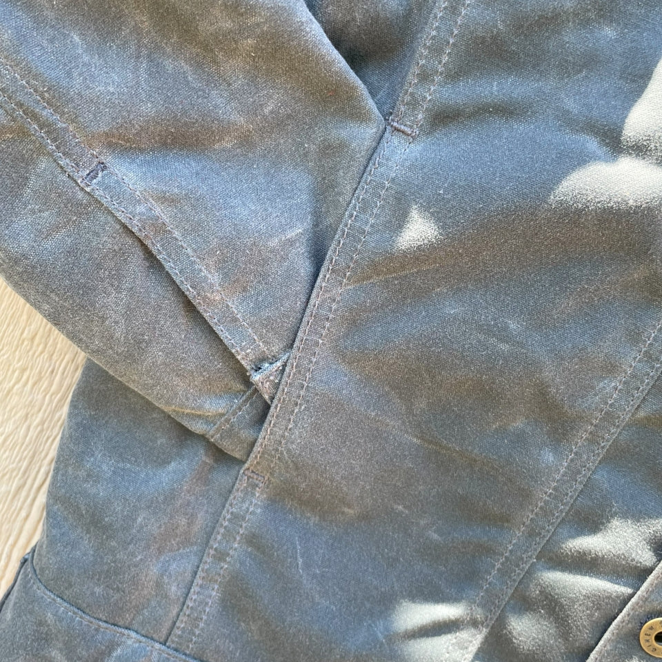 Hand pocket of Grey silver charcoal wax canvas rider coat lined with  Native American design in  brown and cream wool interior made by Indigenous owned Ginew