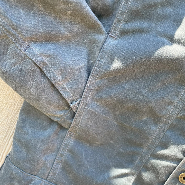 Hand pocket of Grey silver charcoal wax canvas rider coat lined with  Native American design in  brown and cream wool interior made by Indigenous owned Ginew
