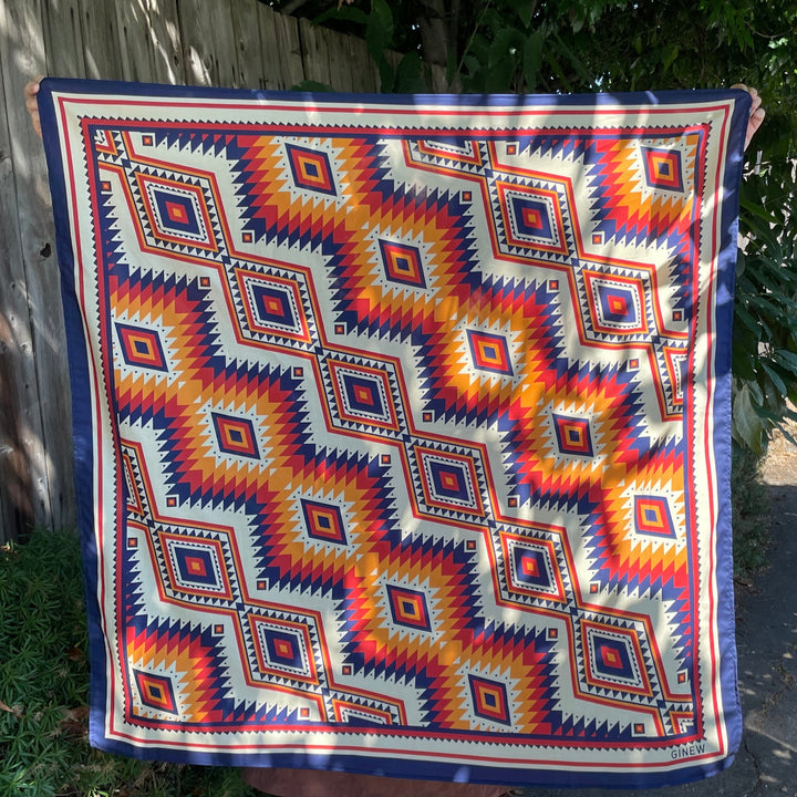 Person holding a colorful Ginew patterned wild rag outdoors