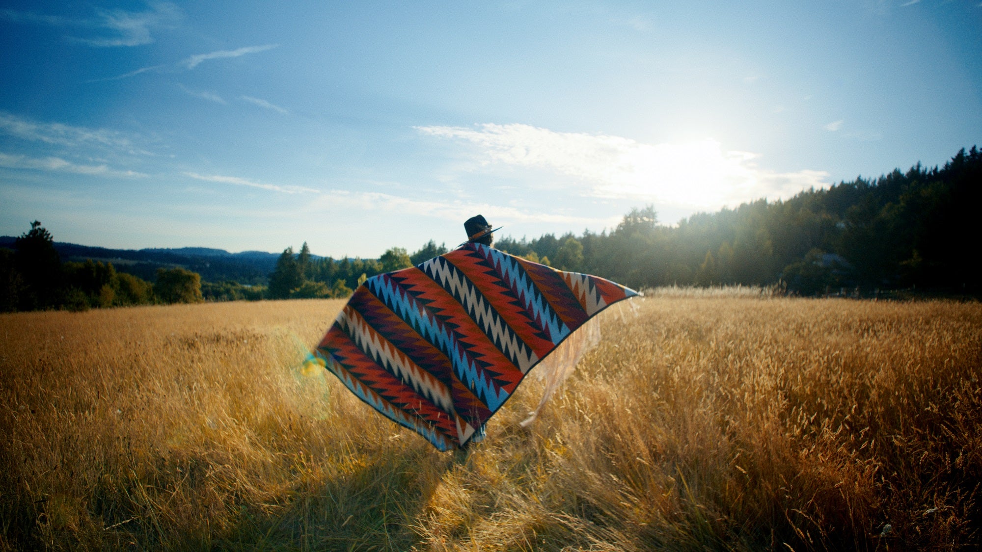 Native American made and designed by Ginew wool blanket held by model in field