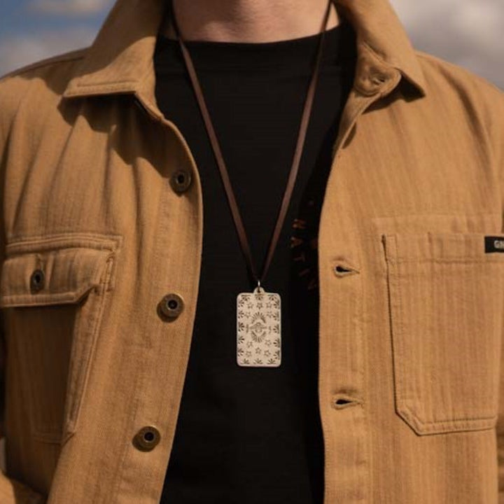 Silver Native American Thunderbird necklace on man wearing a Black Ginew t-shirt and brown tan barn jacket