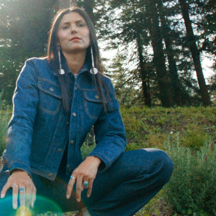 Native American model in selvedge denim jeans and jean coat in woods