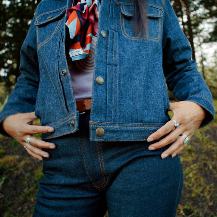 Native American model in wood wearing jean jacket coat with colorful lining. 