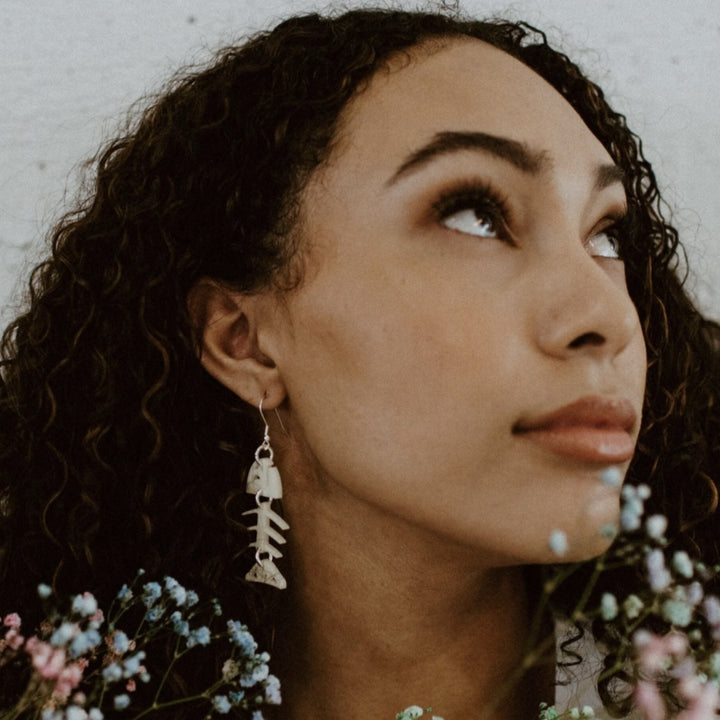 Woman wearing Ivory white salmon fish skeleton earrings Native American designed and made 