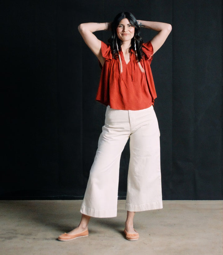 Cream crop carpenter pants and red ruffle shirt on Native American model