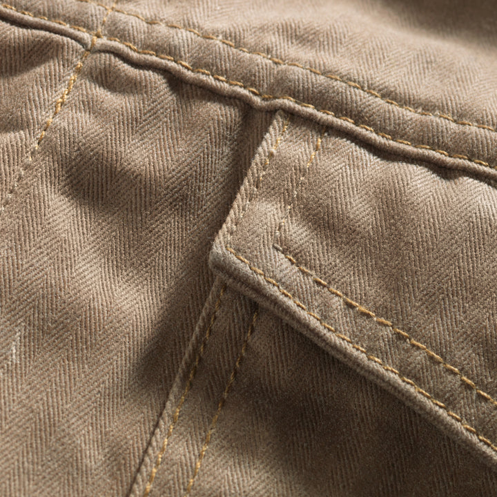 Close up of herringbone patter and front pocket of Brown herringbone coat with wool lining in southwest pattern and quilted sleeves. 