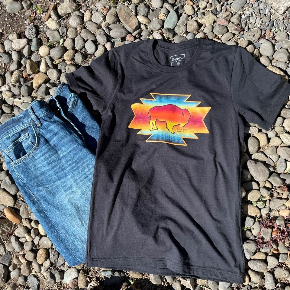 Steven Paul Judd black t-shirt with buffalo image and sunset laying outside on rocks next to jeans