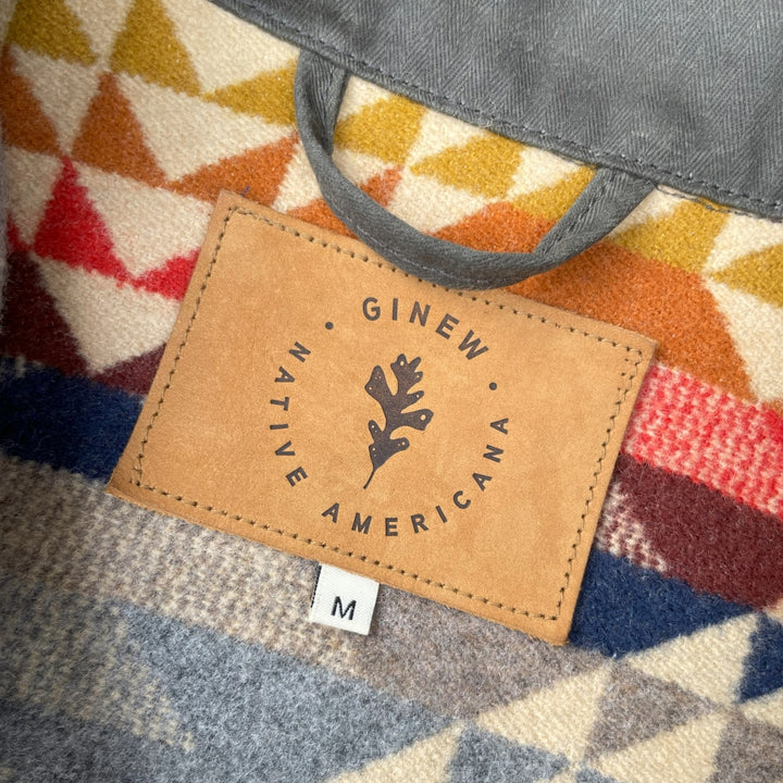 Leather tag on Dark green herringbone rider coat with colorful wool lining by Pendleton and made in USA by Native American, Indigenous Ginew 
