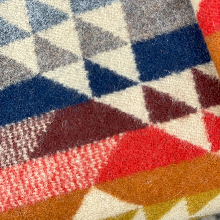 Close-up of a textured fabric with geometric pattern in red, blue, gray, and brown.