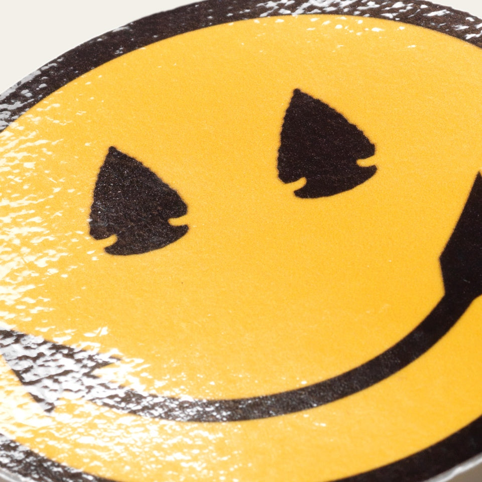 Close up of Native American designed smiley face sticker with arrowhead eyes and smile. 