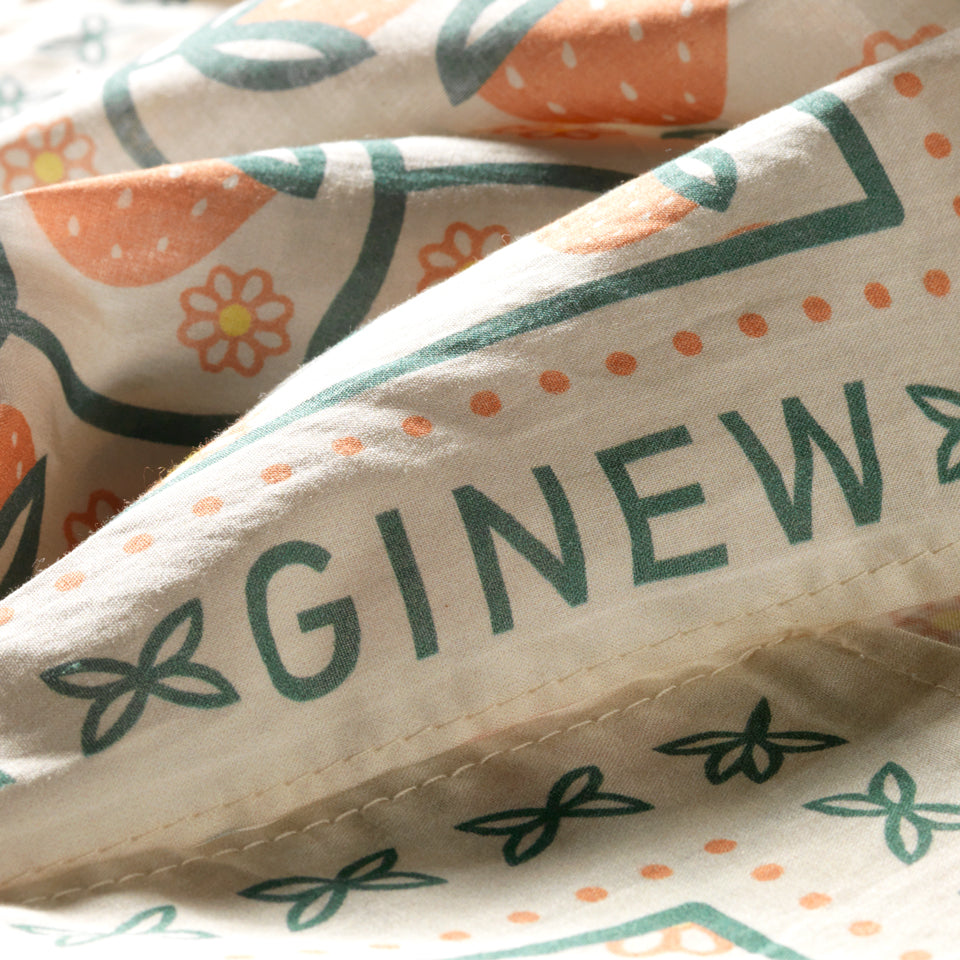 Close up of Ginew on Oneida strawberry bandana  in soft peach orange and green on cream cotton fabric