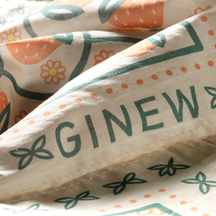 Close up of Ginew on Oneida strawberry bandana  in soft peach orange and green on cream cotton fabric