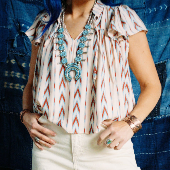 Front close up of model wearing Native American Ginew Stripe Ruffle shirt  in red, turquoise blue, cream 