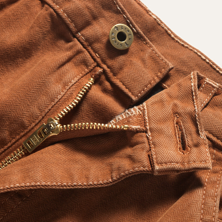 Herringbone twill pants in orange adobe. Detail view of zipper-fly and button on the waist of the Superior Pant in Adobe.