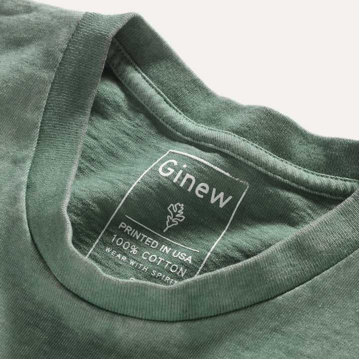Close up of collar on Native American Ginew's cotton tie dye tee in green, off-white and maroon with iconic Ojibwe thunderbird in army green