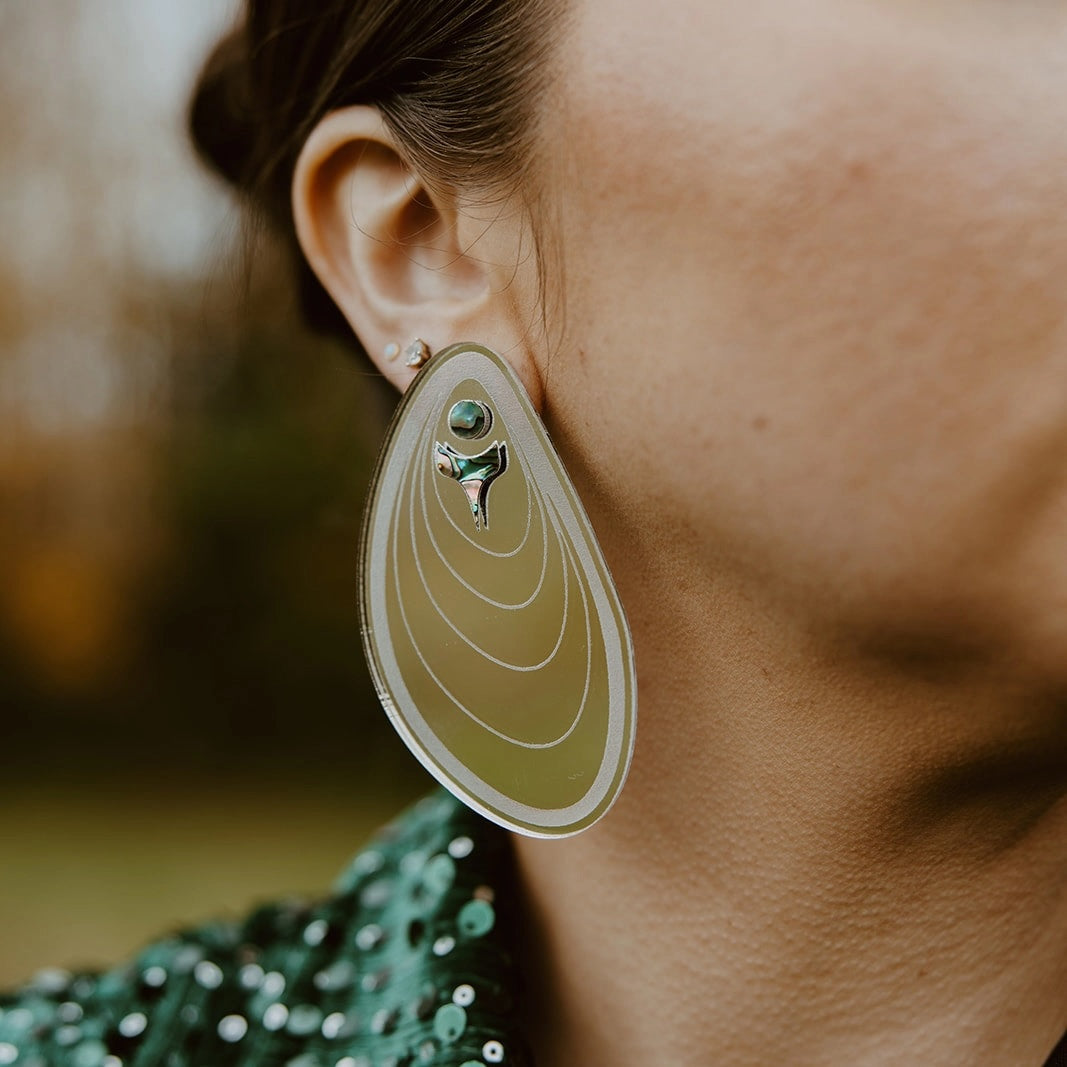 Indigenous handmade earrings in tidal ripple form worn on Native American woman with abalone inlay