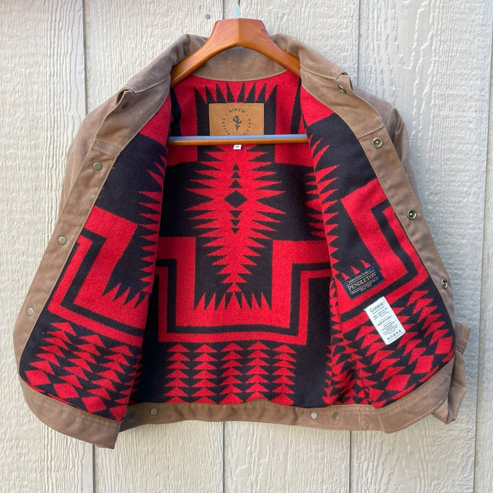 Brown jacket with red and black geometric pattern on a wooden hanger against a light wooden panel background