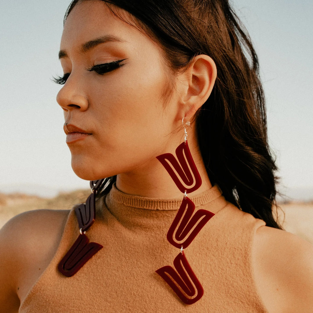 Indigenous woman wearing Native American made stacked earrings in maroon