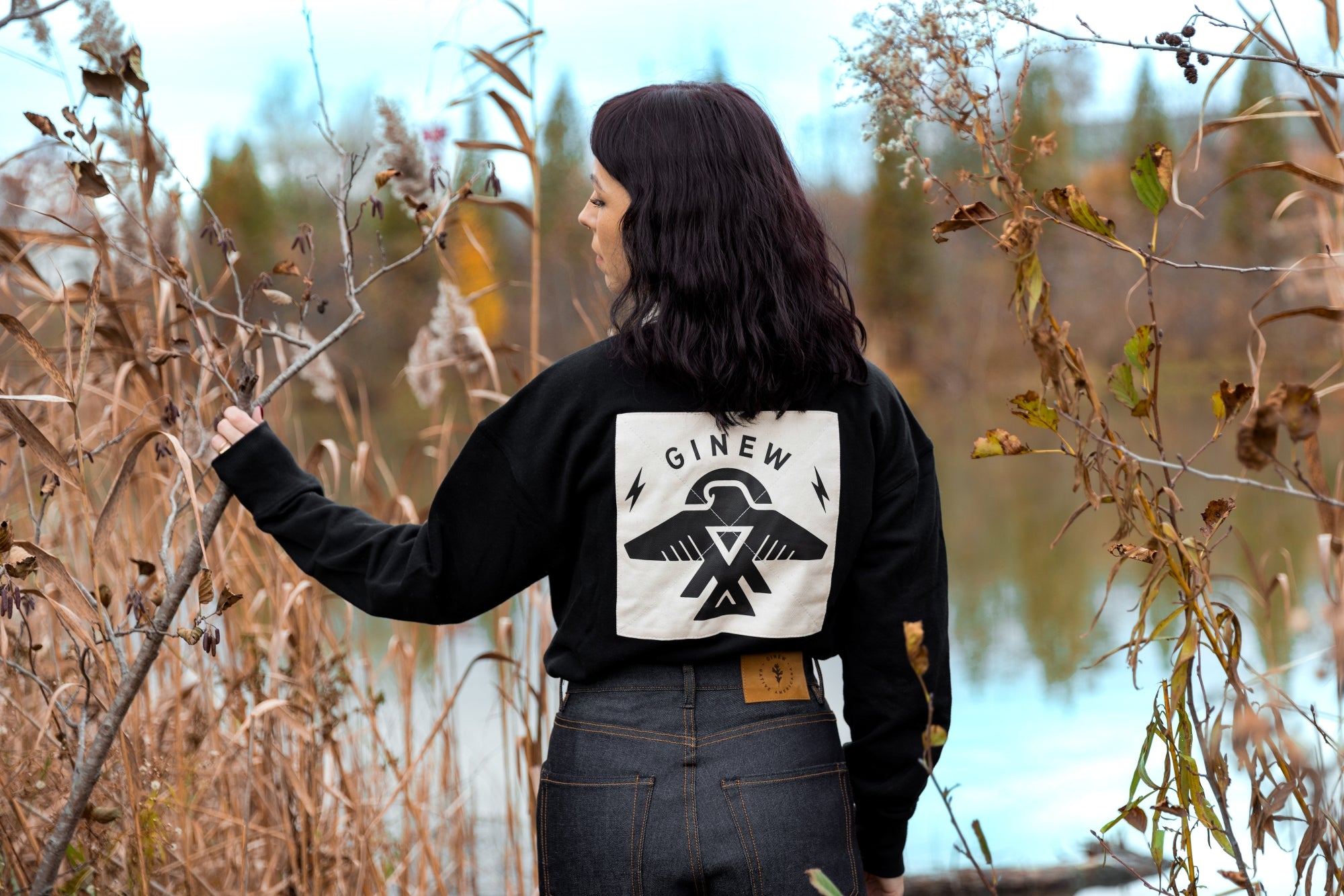 Native American wearing Ginew Rugby shirt by lake 