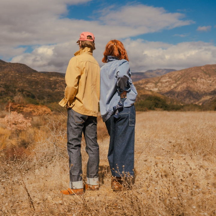 Back of barn jackets in blue and tan on couple in nature