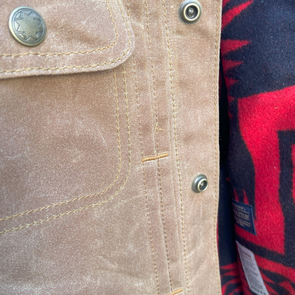 Button close up on Womens brown wax canvas type 2 coat with red and black Pendleton lining with Native American Ginew tag