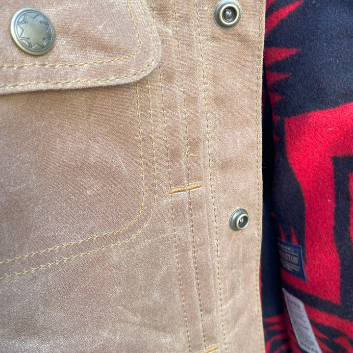 Button close up on Womens brown wax canvas type 2 coat with red and black Pendleton lining with Native American Ginew tag